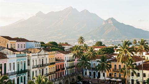 Vue éditoriale réaliste d’un itinéraire colombien avec les façades colorées de Carthagène des Indes au premier plan et les montagnes andines dans la brume au loin.